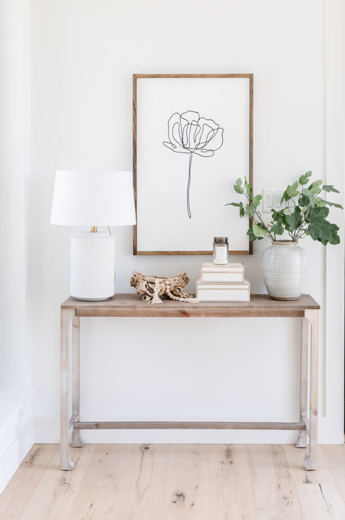 Image of entry way table with a picture of a flower hanging up behind it.