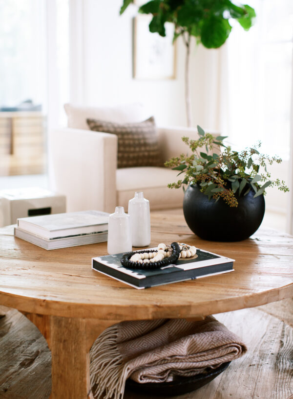 Image of coffee table with a planter, books, beads and vases on it