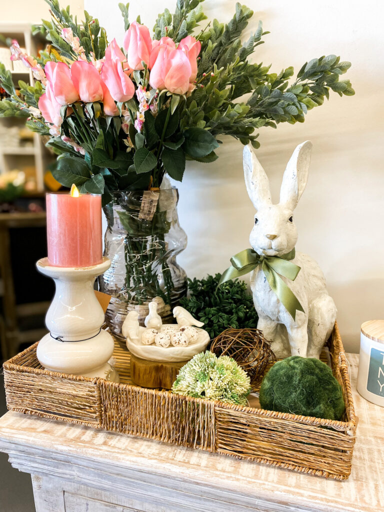 image of basket with greenery, candlestick with a candle on it, a bunny and a vase with florals in it for spring home decor